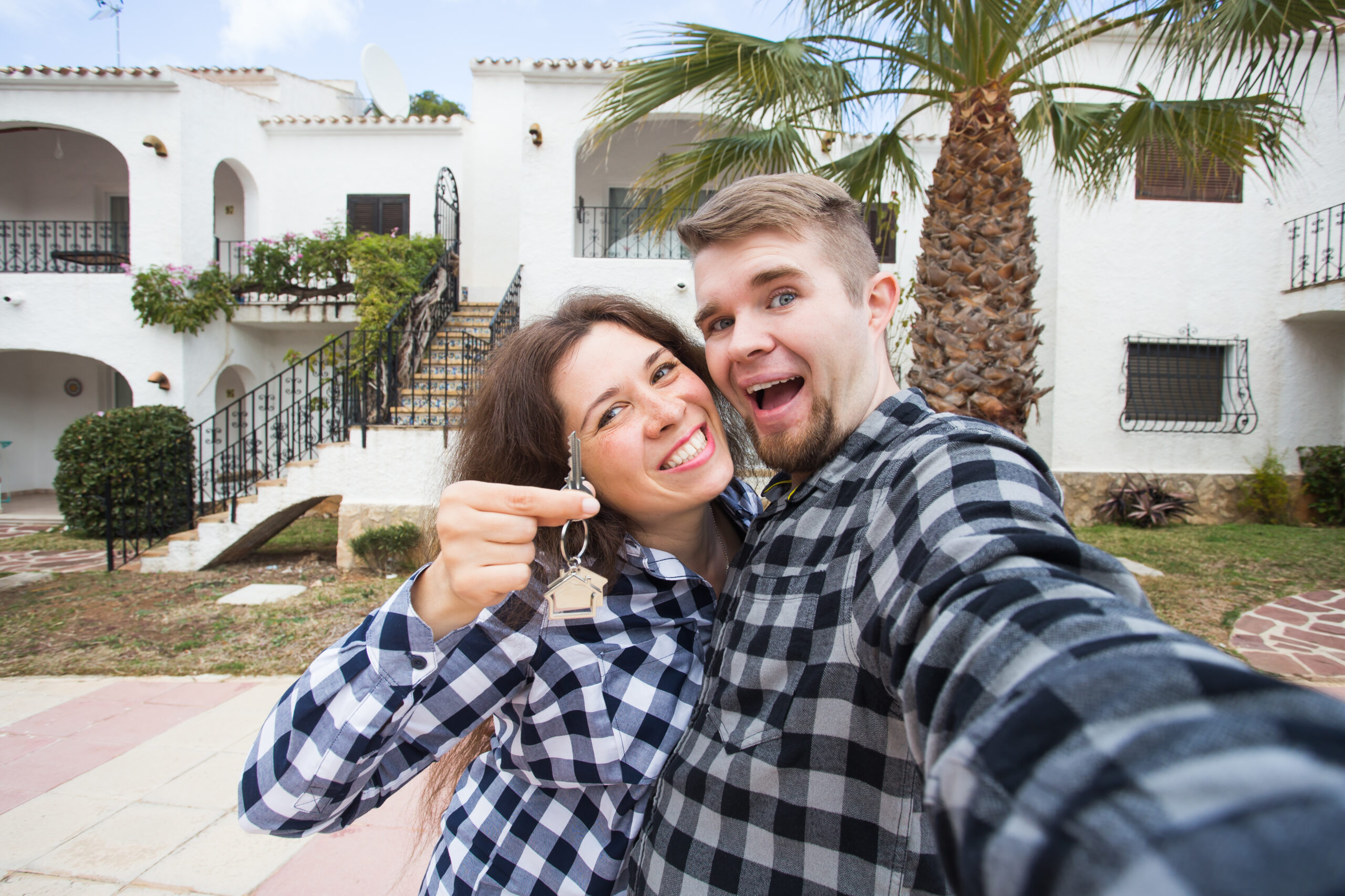 Happy young couple outside a Mediterranean property in Spain, illustrating first-time home ownership